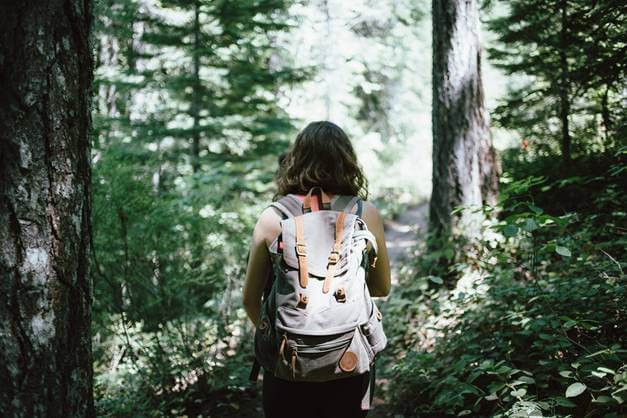 A woman hiking through a forest with a backpack